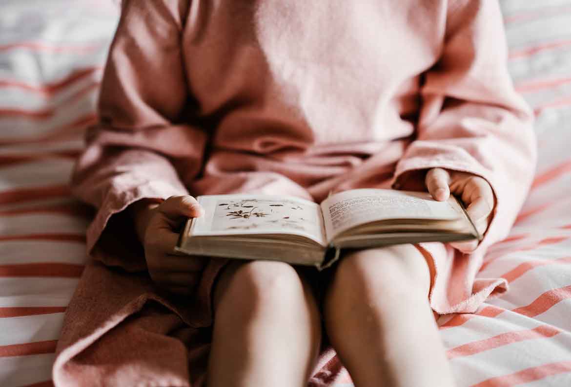 chica leyendo un libro sentada en la cama