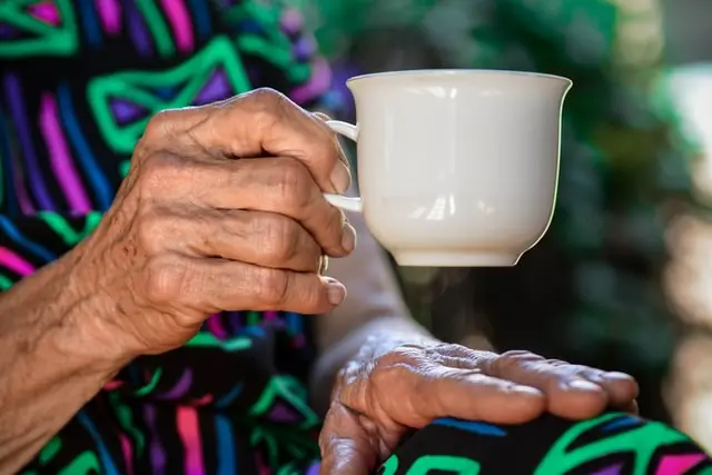 manos de mujer anciana sujetando una taza